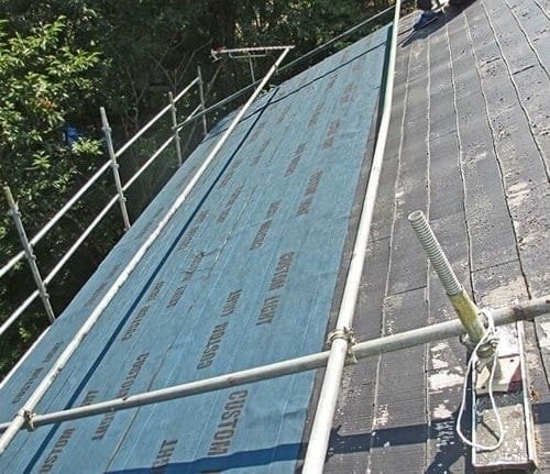 カバー工法で屋根に防水シートを張っていく様子